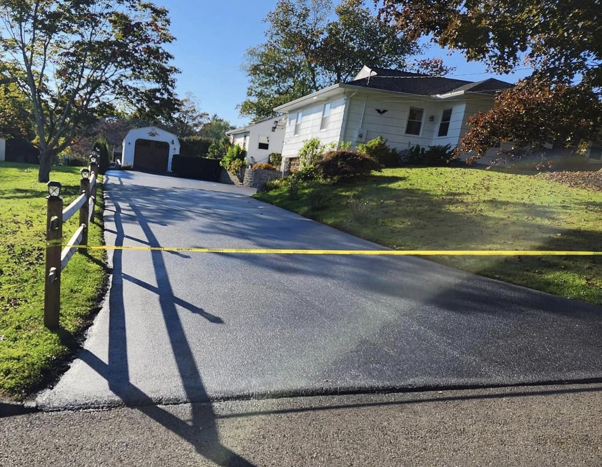 A crew from Fasano's Sealcoating is seen paving a new asphalt driveway in Meriden, CT. The team operates heavy machinery to lay down and smooth the fresh asphalt, ensuring a level and durable surface. Fasano's Sealcoating offers professional paving services throughout Connecticut, delivering high-quality results for residential and commercial properties.